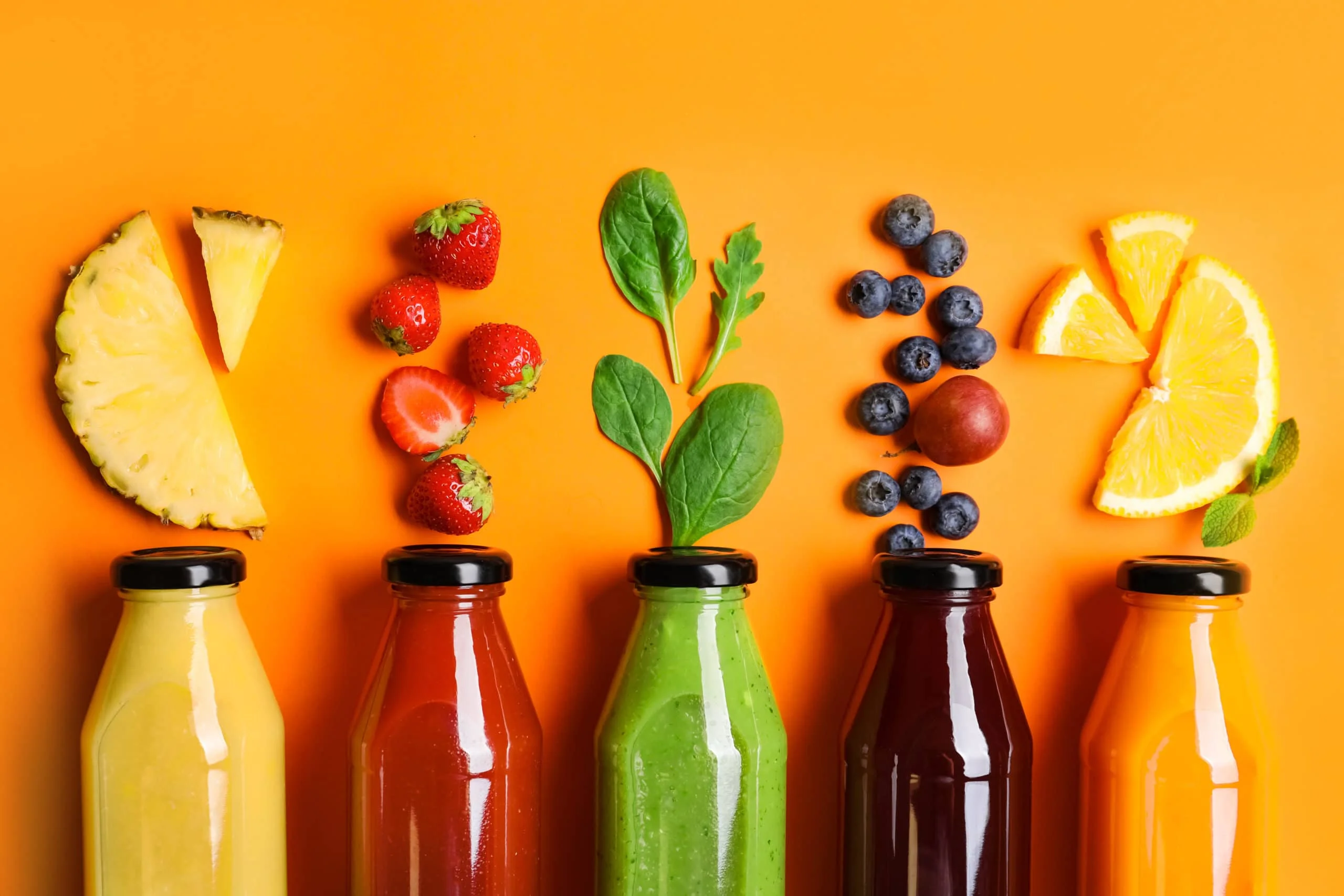 Colorful assortment of fresh juices and fruits on a vibrant background