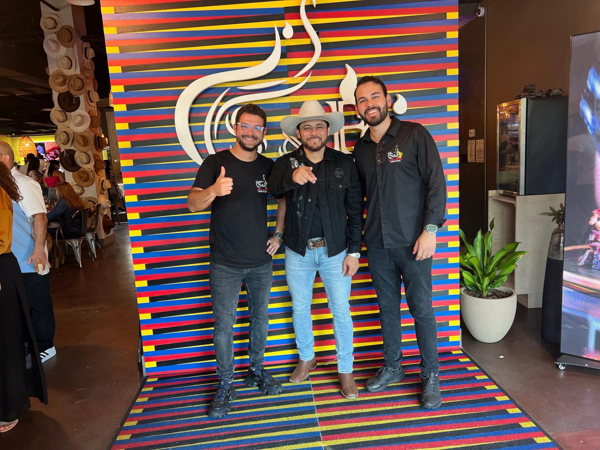Three restaurant staff members posing in front of a colorful backdrop