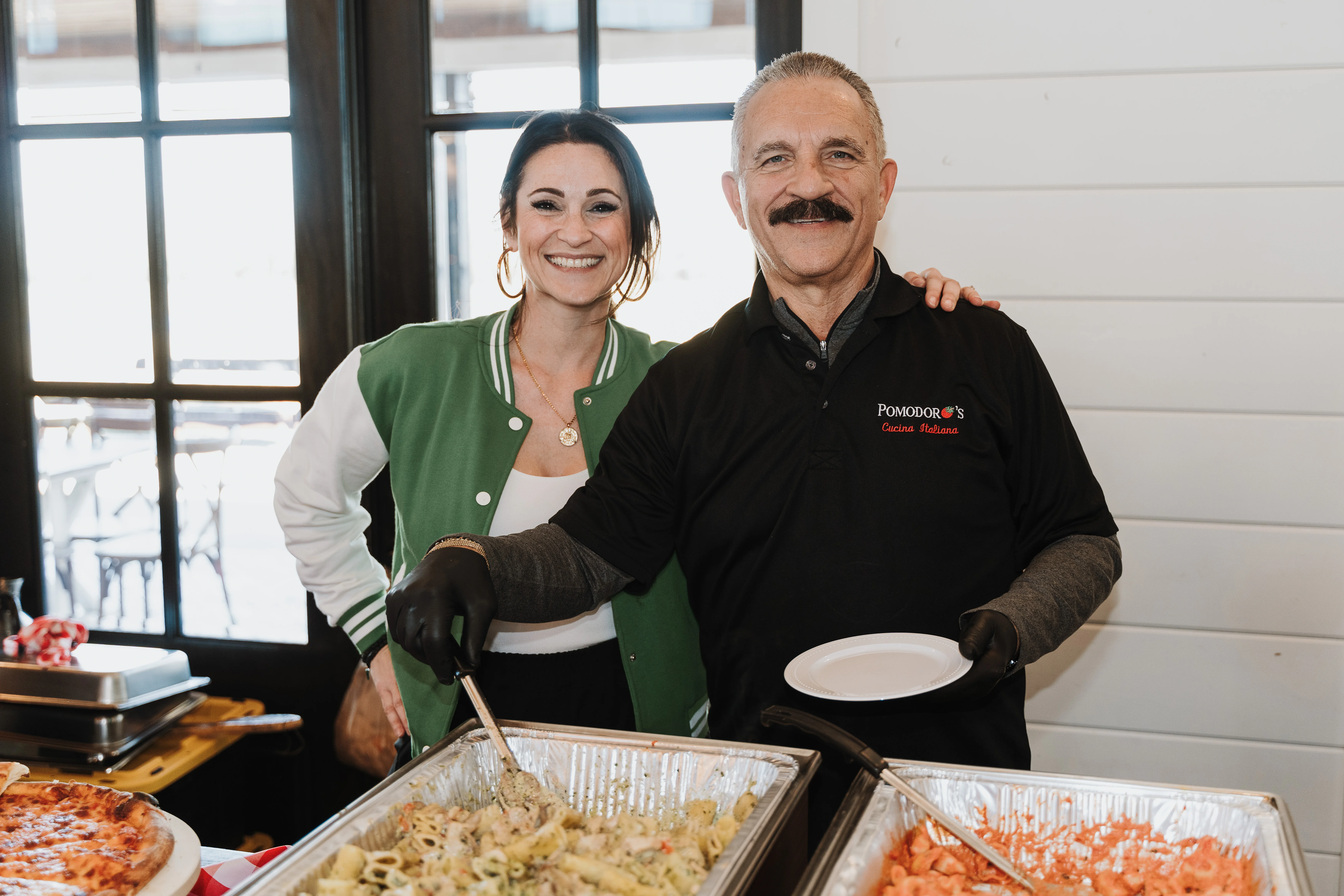 Chefs serving Italian pasta dishes at a restaurant event