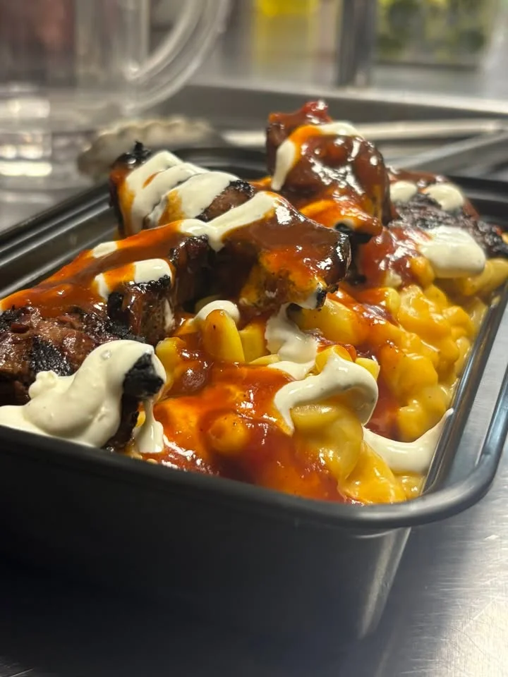A delicious meal combining macaroni and cheese topped with grilled meat and drizzled with a tangy sauce and sour cream.