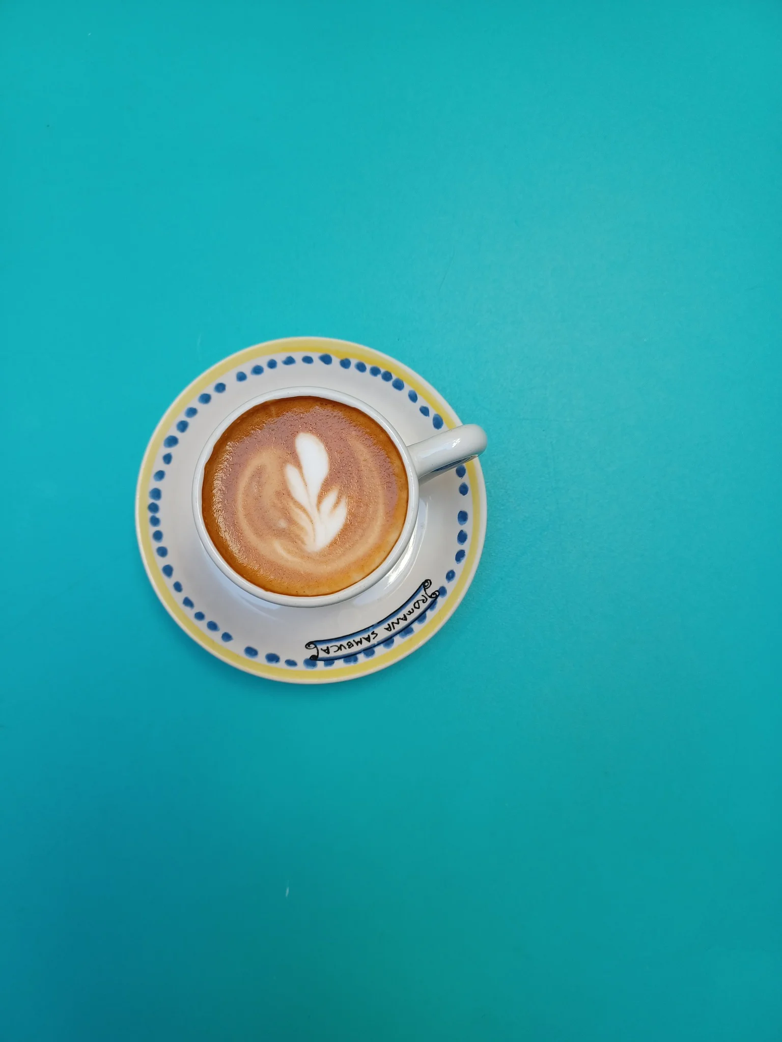 Artisan latte with beautiful foam art on a turquoise table