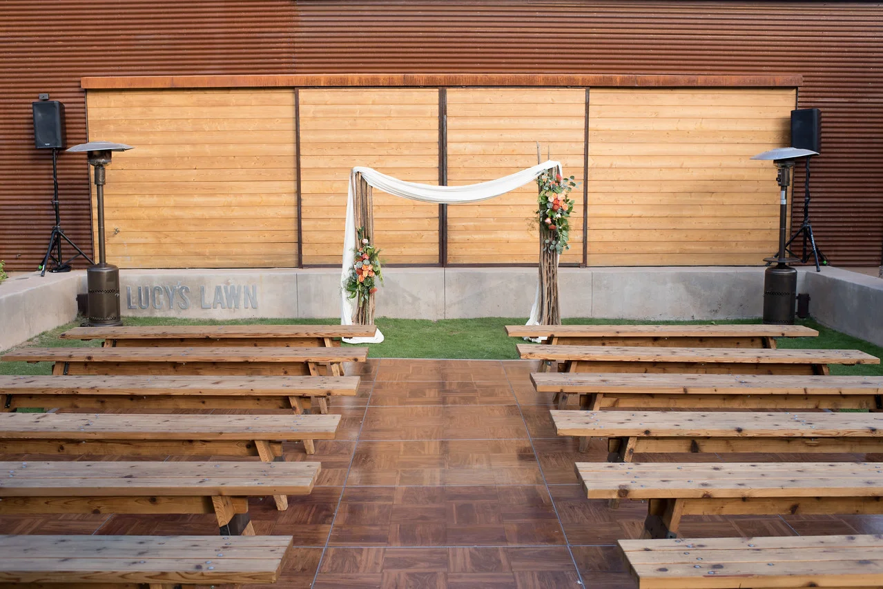 Outdoor wedding ceremony setup with wooden benches and floral arch