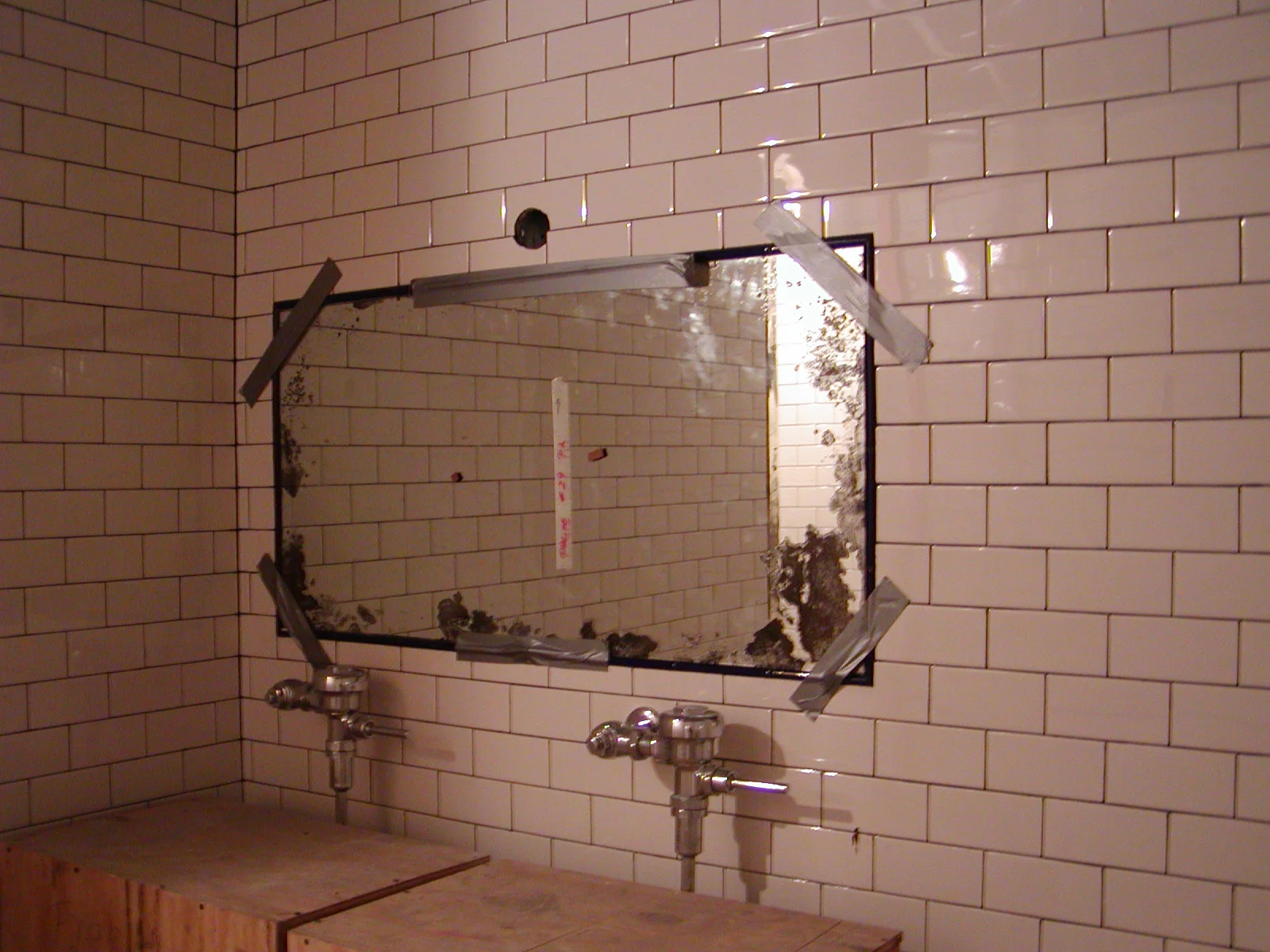 Under-construction restroom with tiled walls and a mirror frame