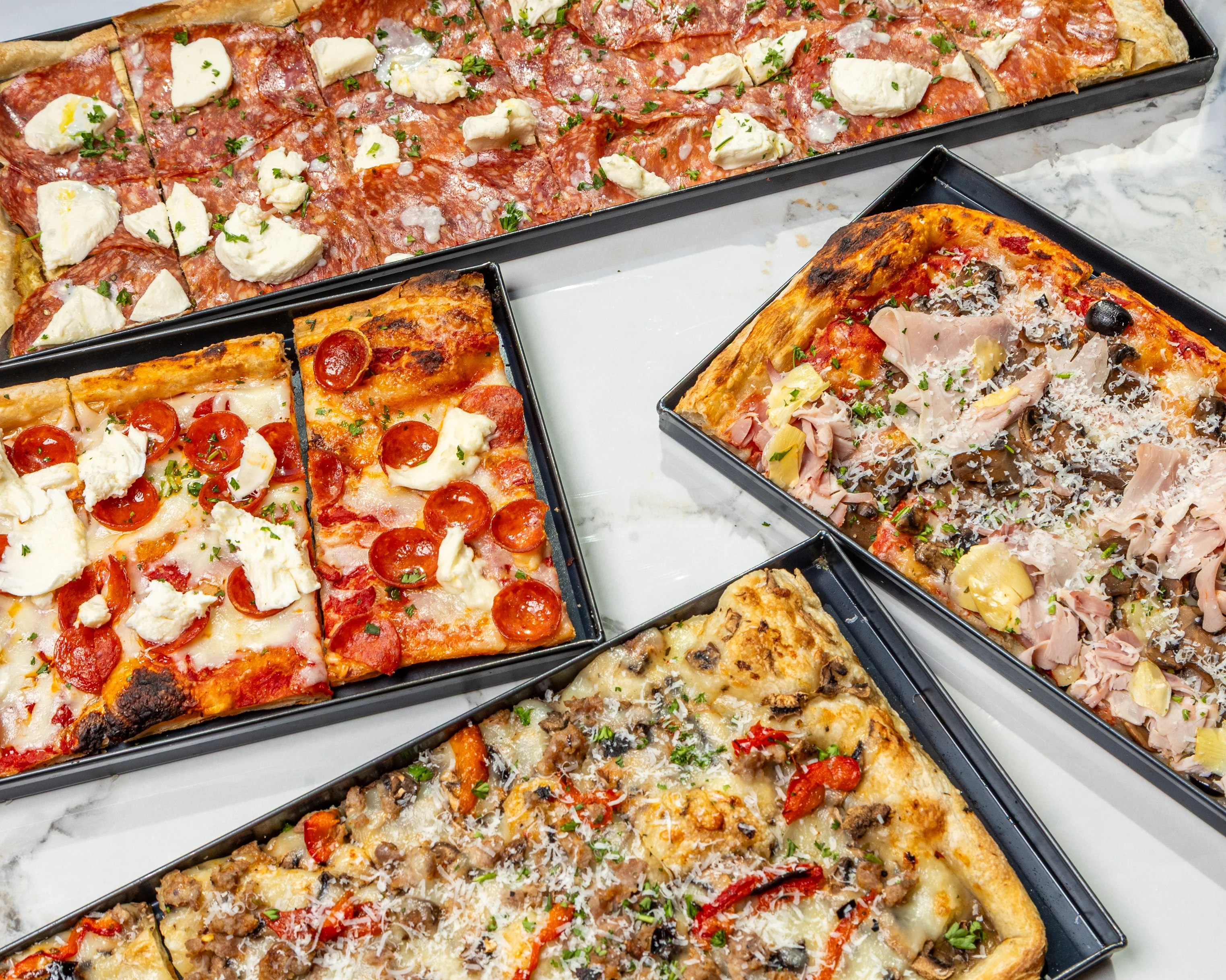Assorted Italian pizza varieties on a marble table