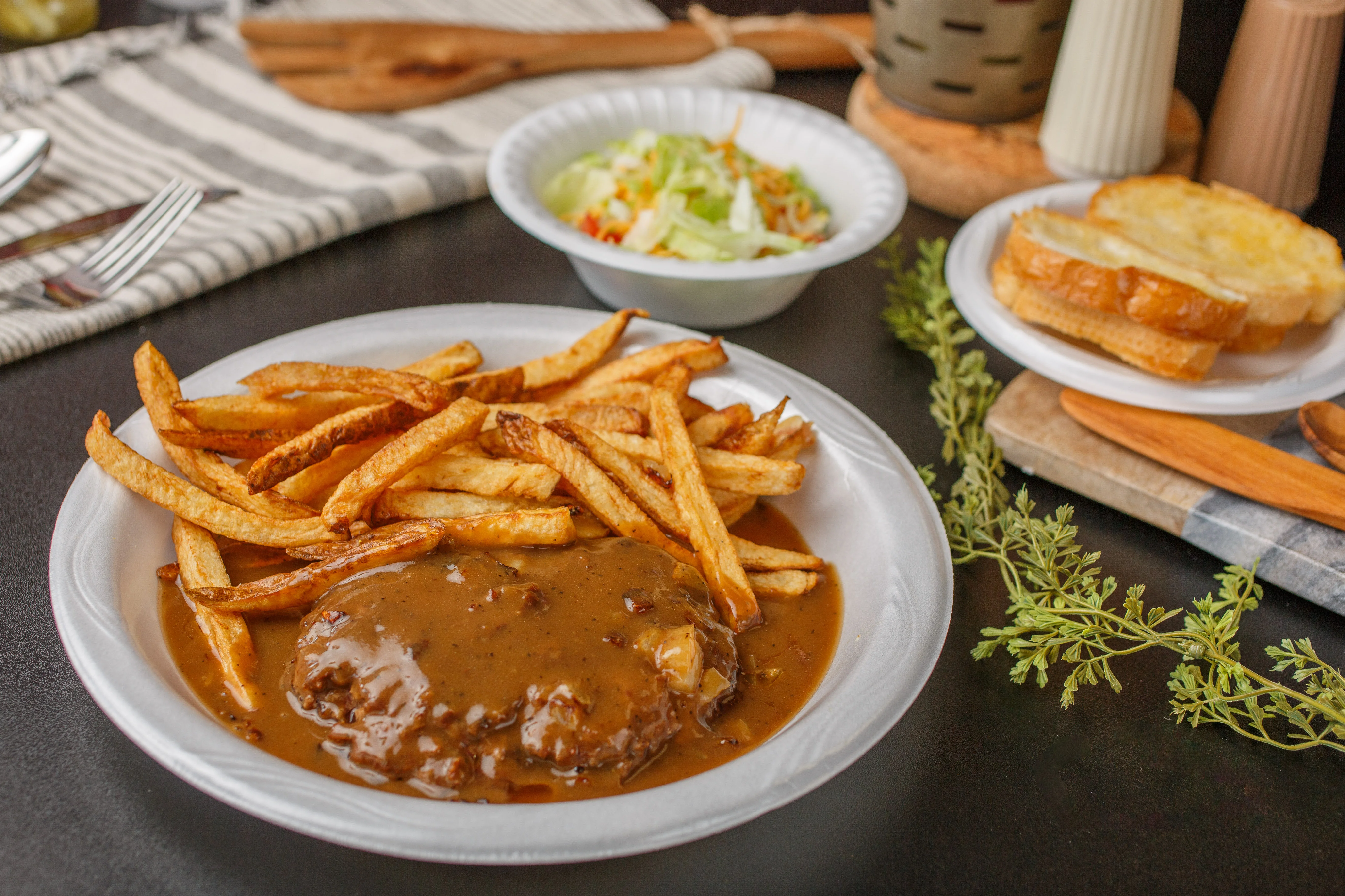 Plate of fries with gravy and a side of coleslaw and garlic bread.