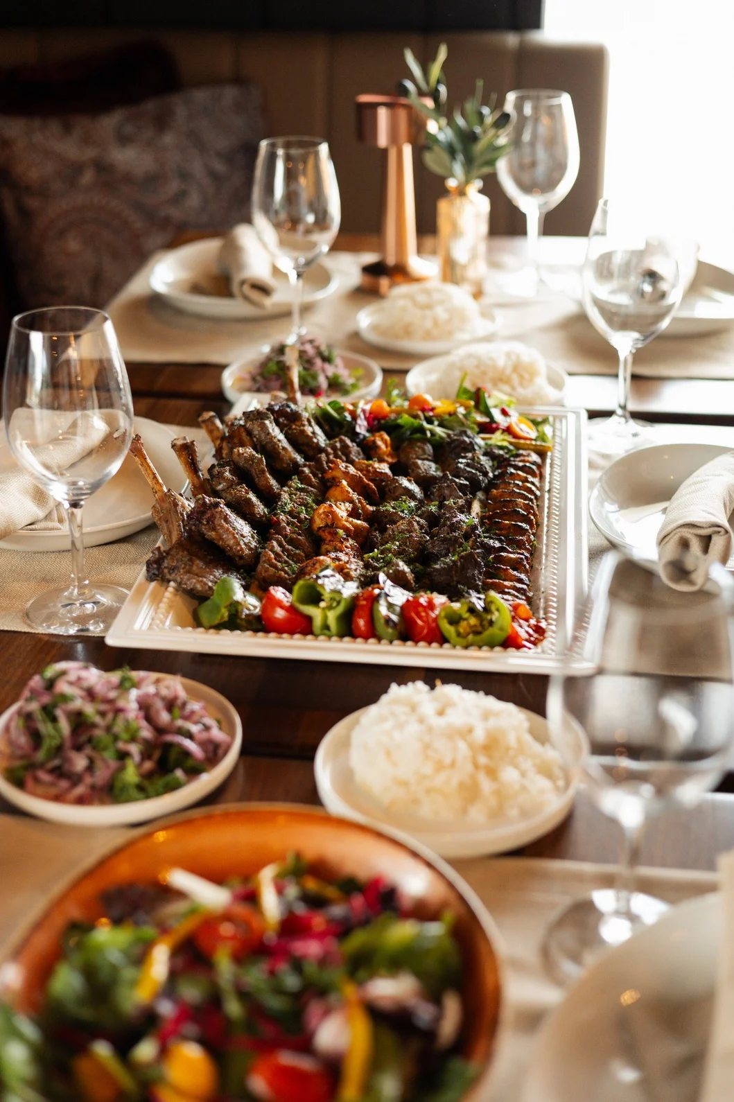 Grilled skewers of various meats are being cooked over charcoal, creating a smoky atmosphere.