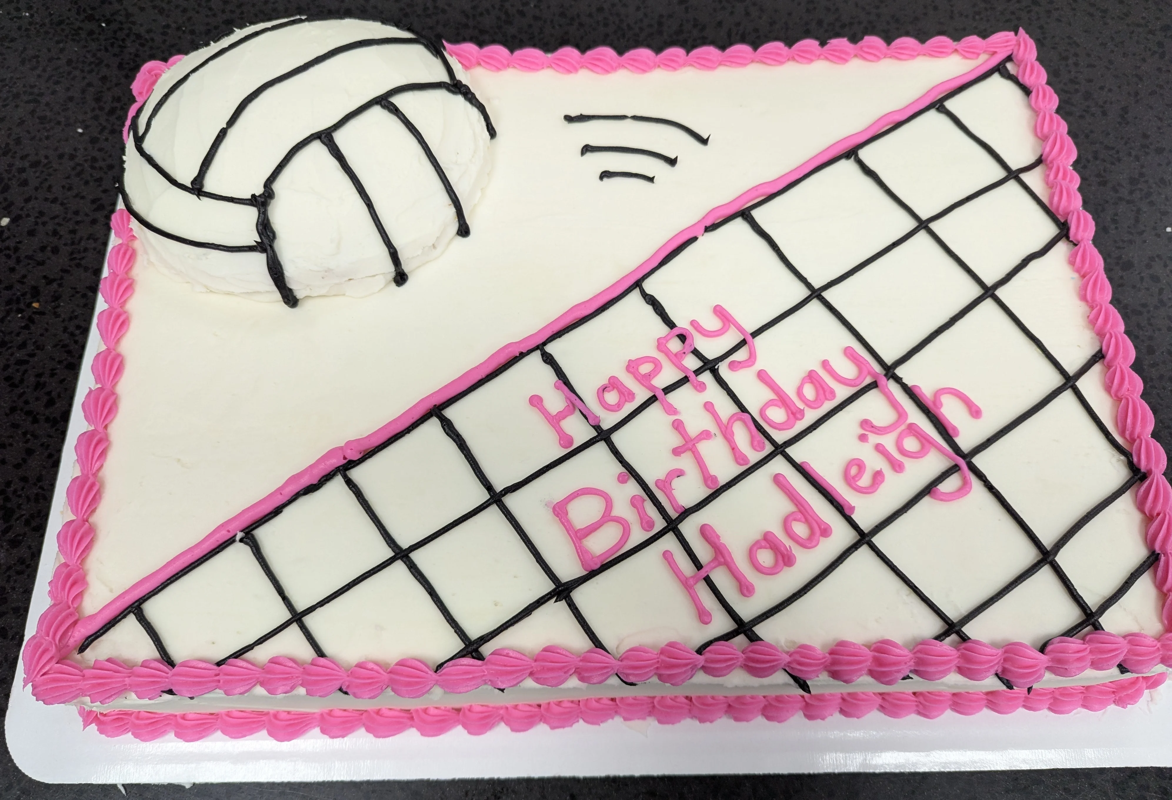 Sheet cake with pink borders and decorations drawn on to look like a volleyball & net.