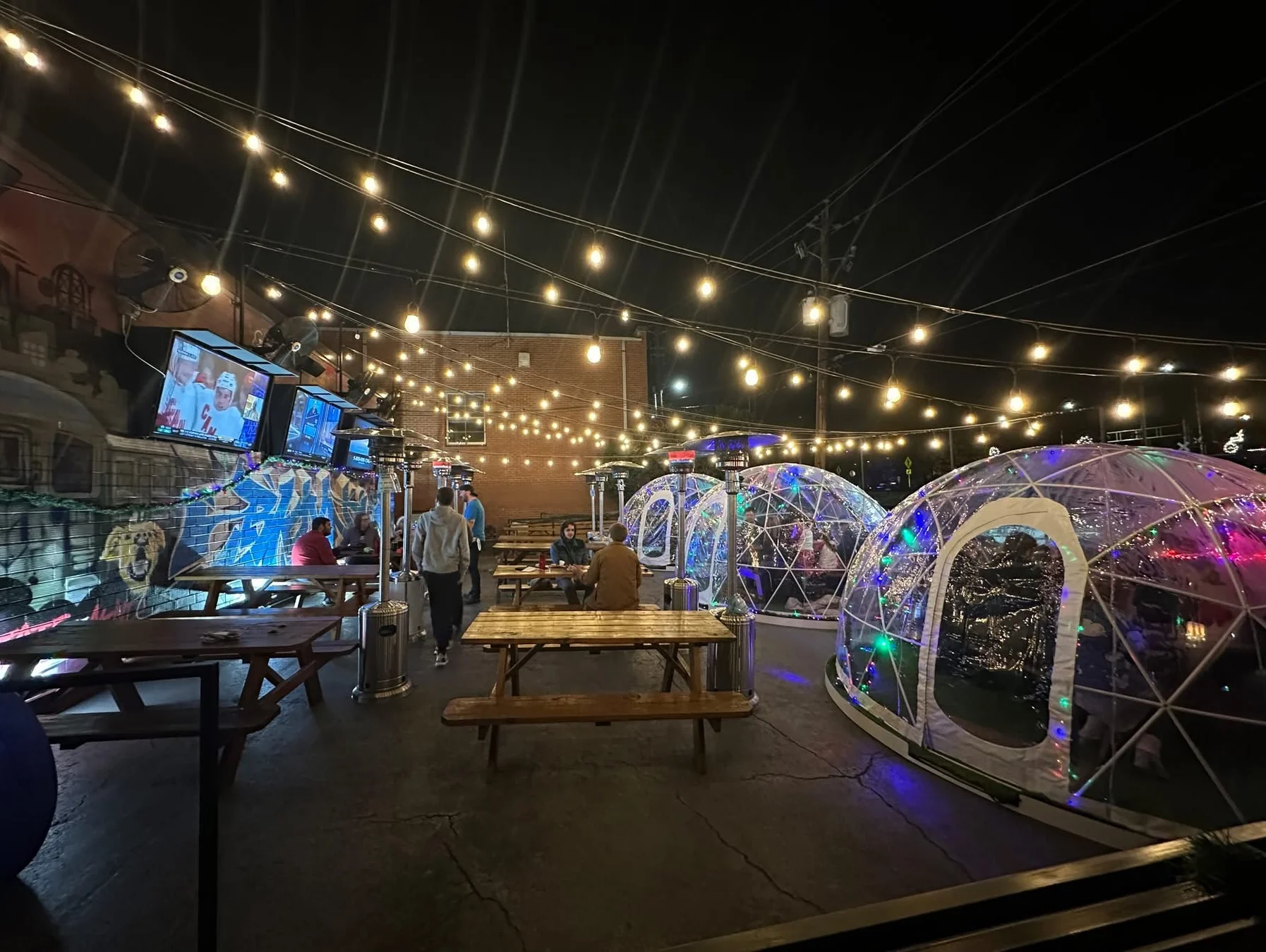 Outdoor patio at night with illuminated igloos for dining.
