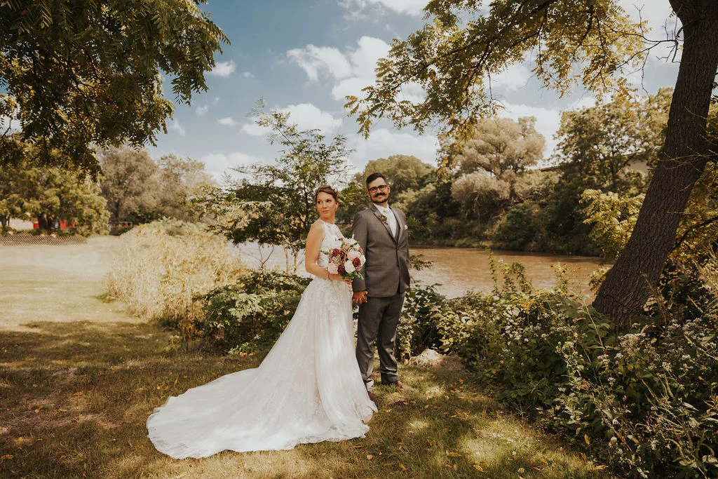 A couple standing at the banks of the Baraboo River in the grass