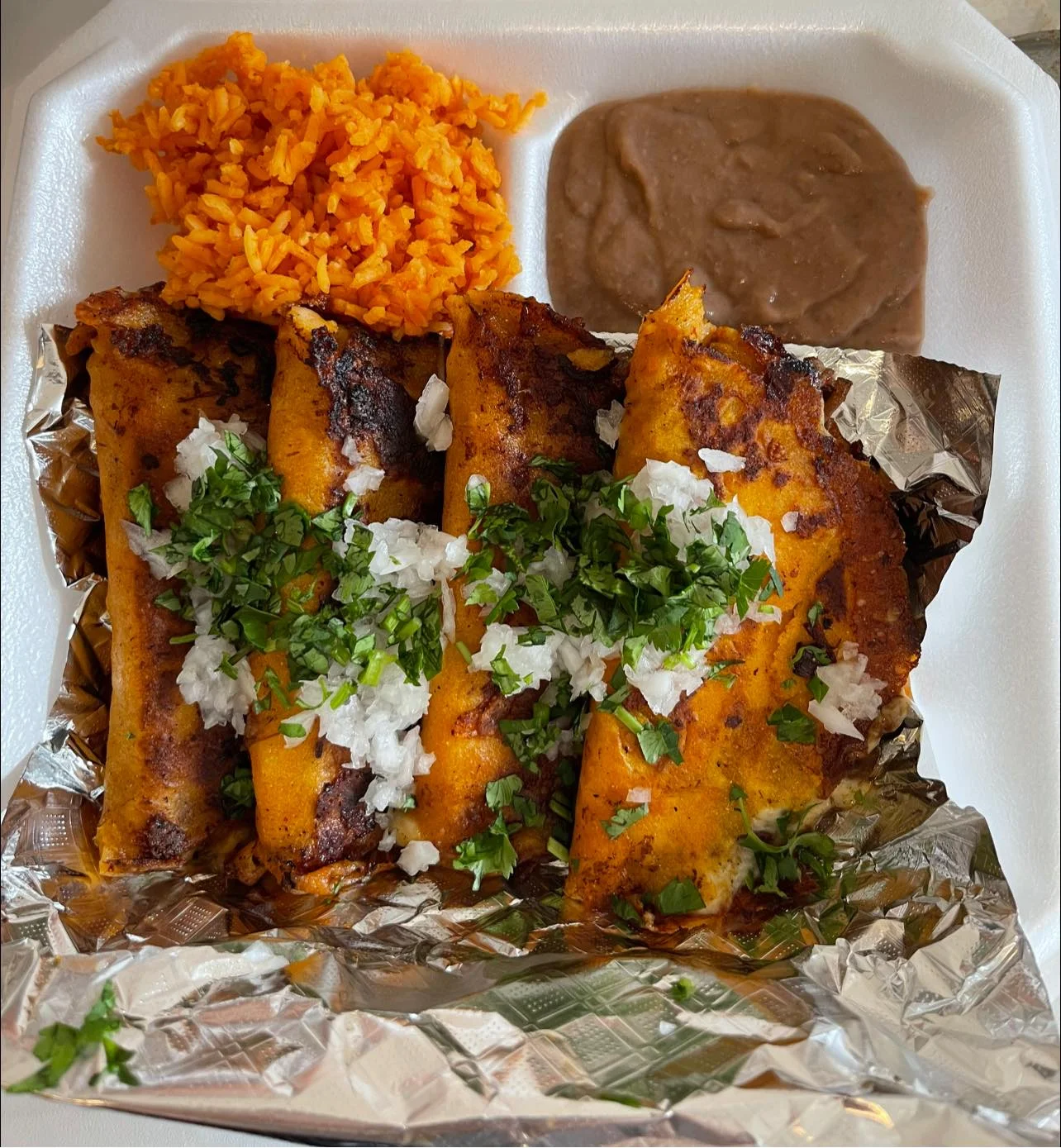 Plate of Mexican enchiladas topped with cilantro and onions