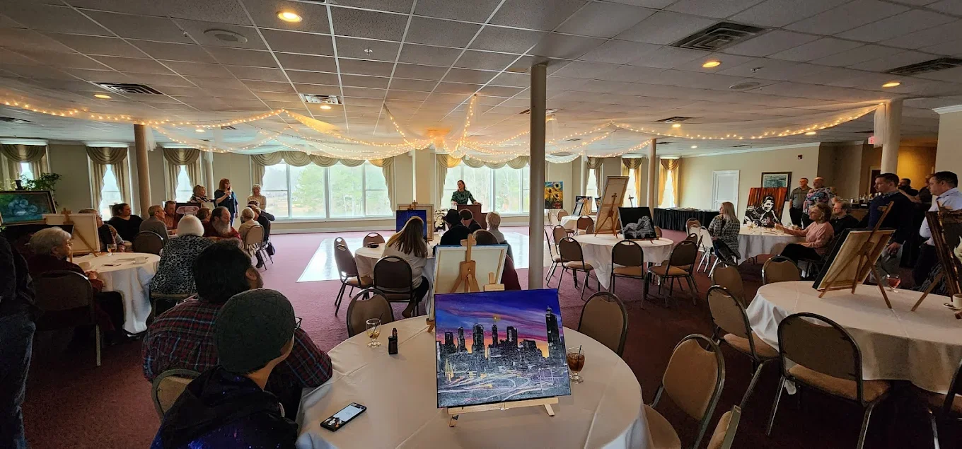 Art event in a spacious banquet hall with attendees and artwork displays