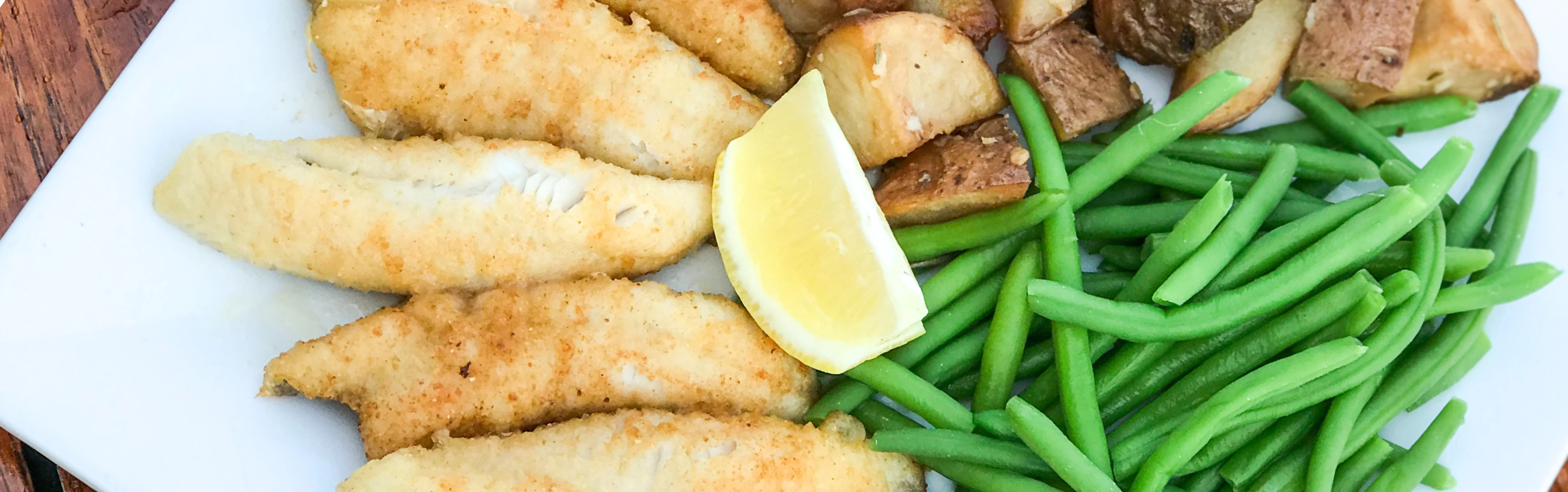 Southern fried catfish with sides of green beans and roasted potatoes