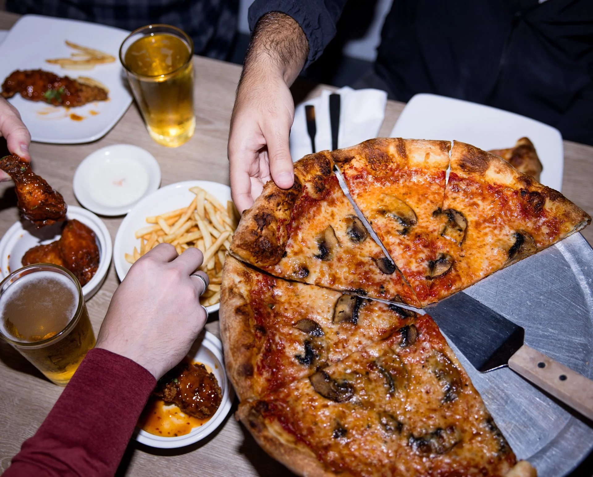 Sicilian-style mushroom pizza with buffalo wings, fries, and beer