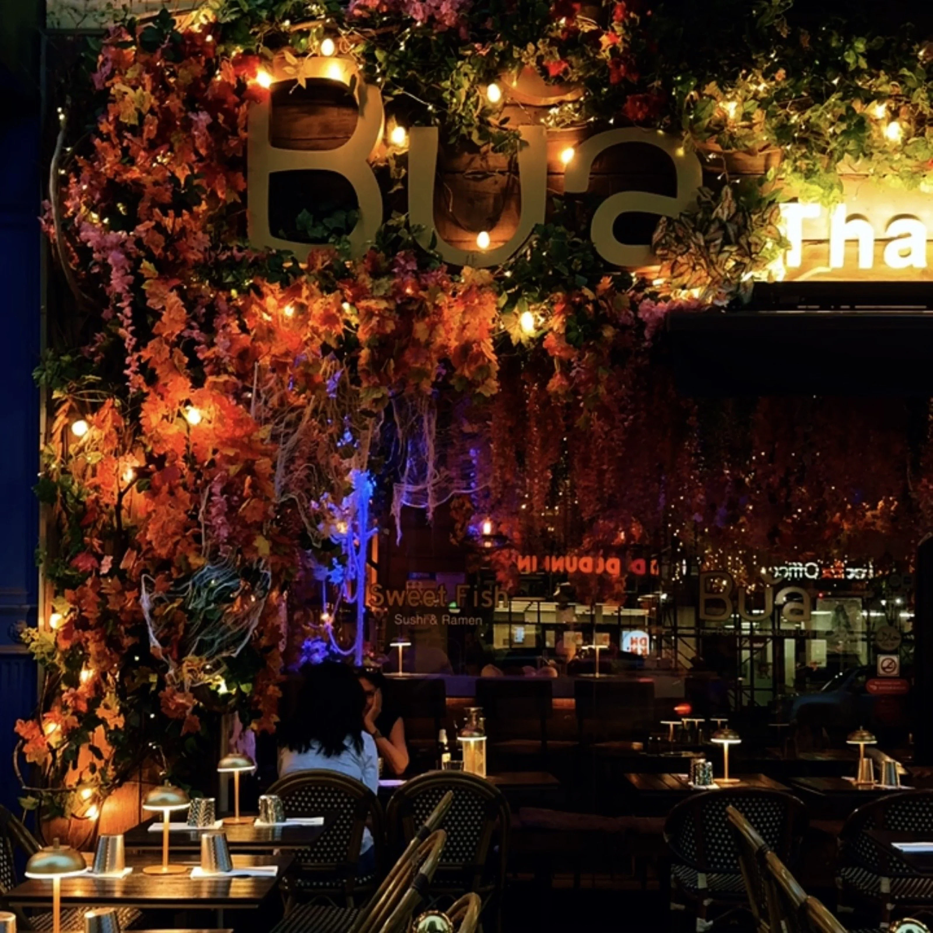Charming restaurant exterior adorned with vibrant foliage and warm lights
