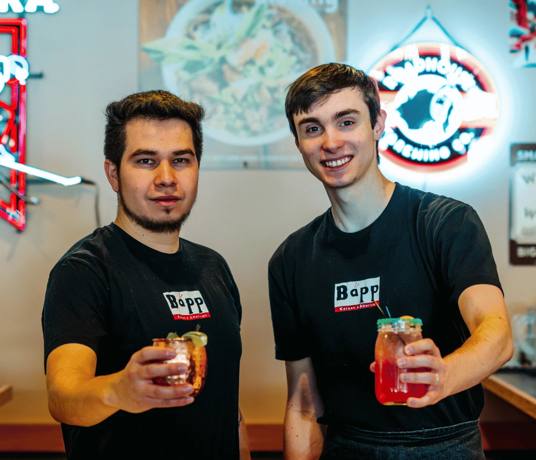 Bartenders showcasing colorful cocktails at a lively bar