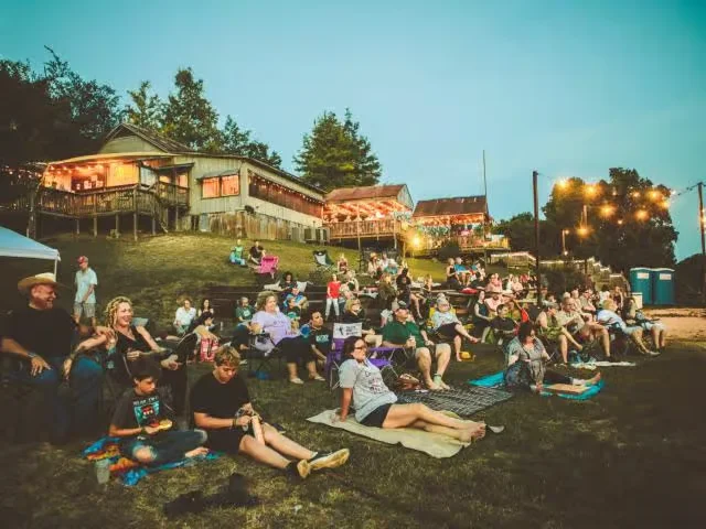 Community gathering at night with lights and stage in Bastrop