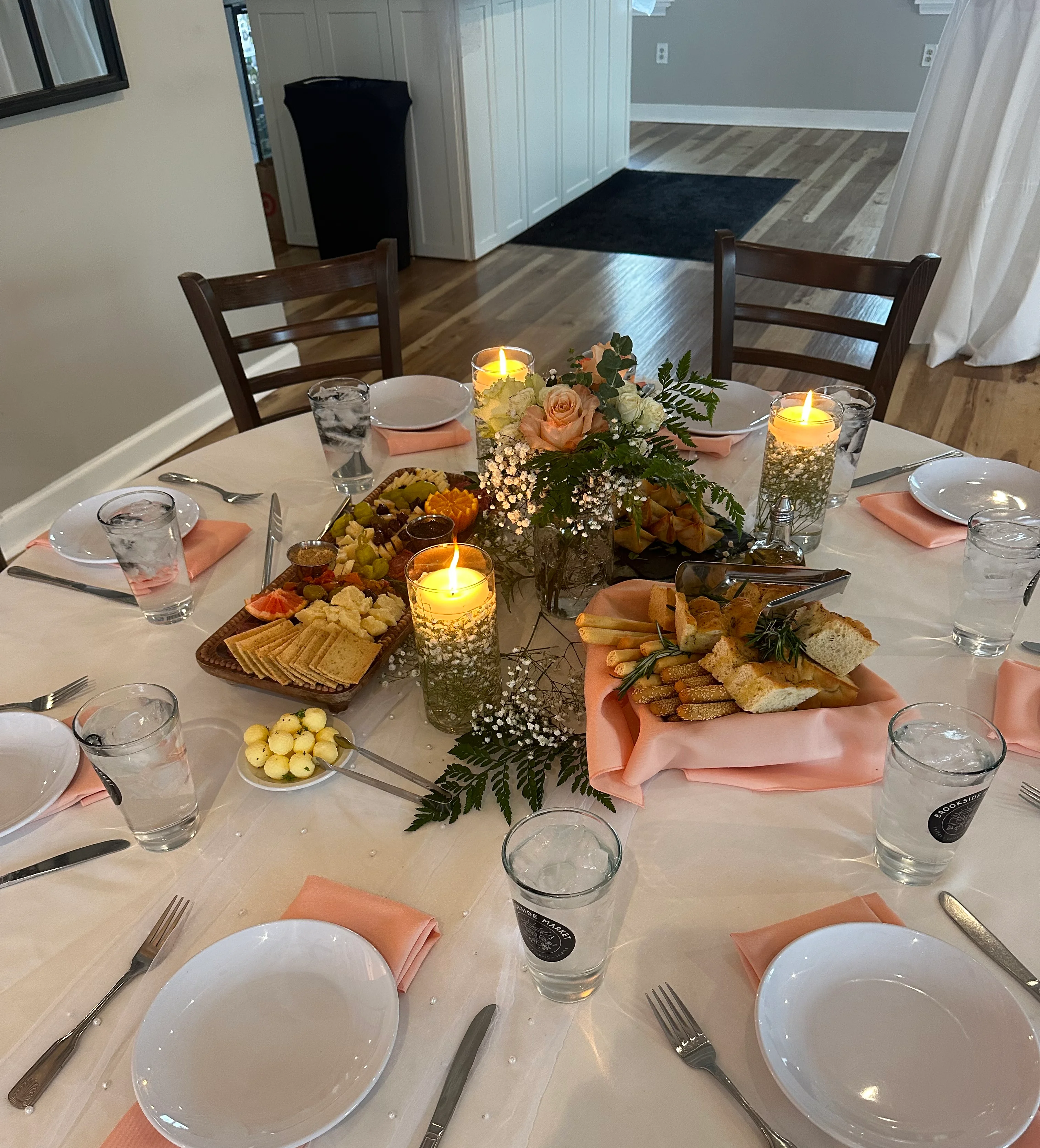 Elegant dining table set with food, candles, and floral centerpiece.