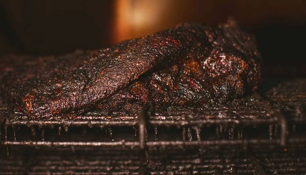 Smoked brisket resting on a grill rack