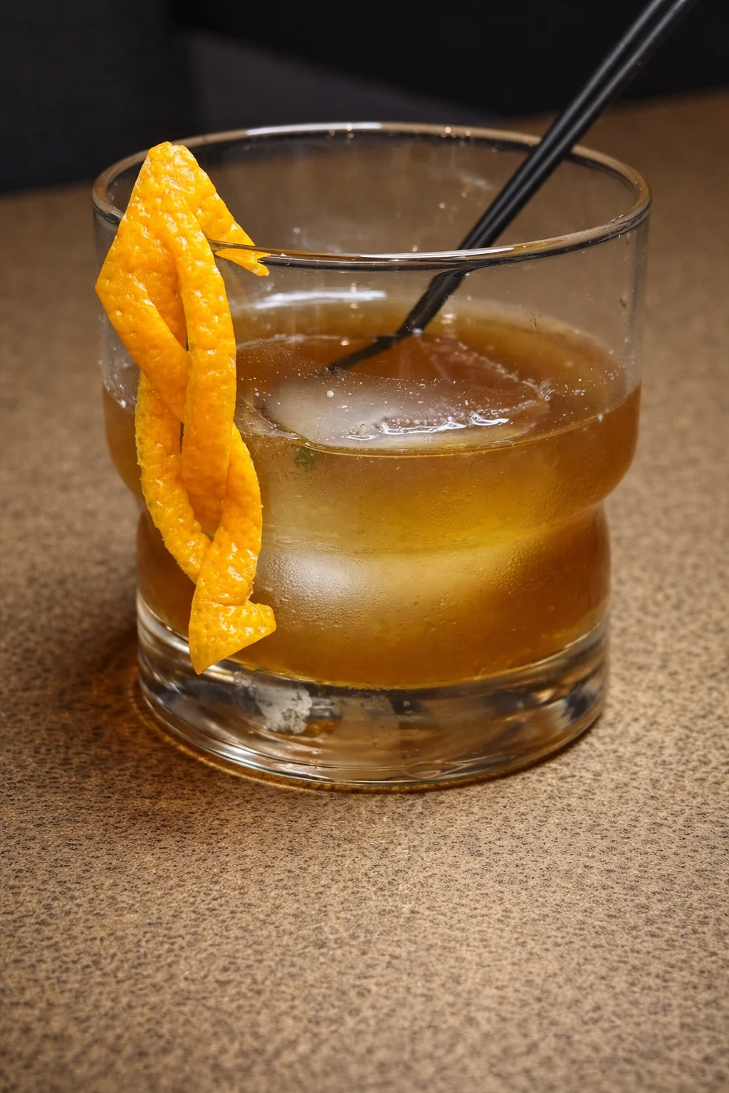 A Coconut Old Fashioned cocktail garnished with a cherry and orange slice.