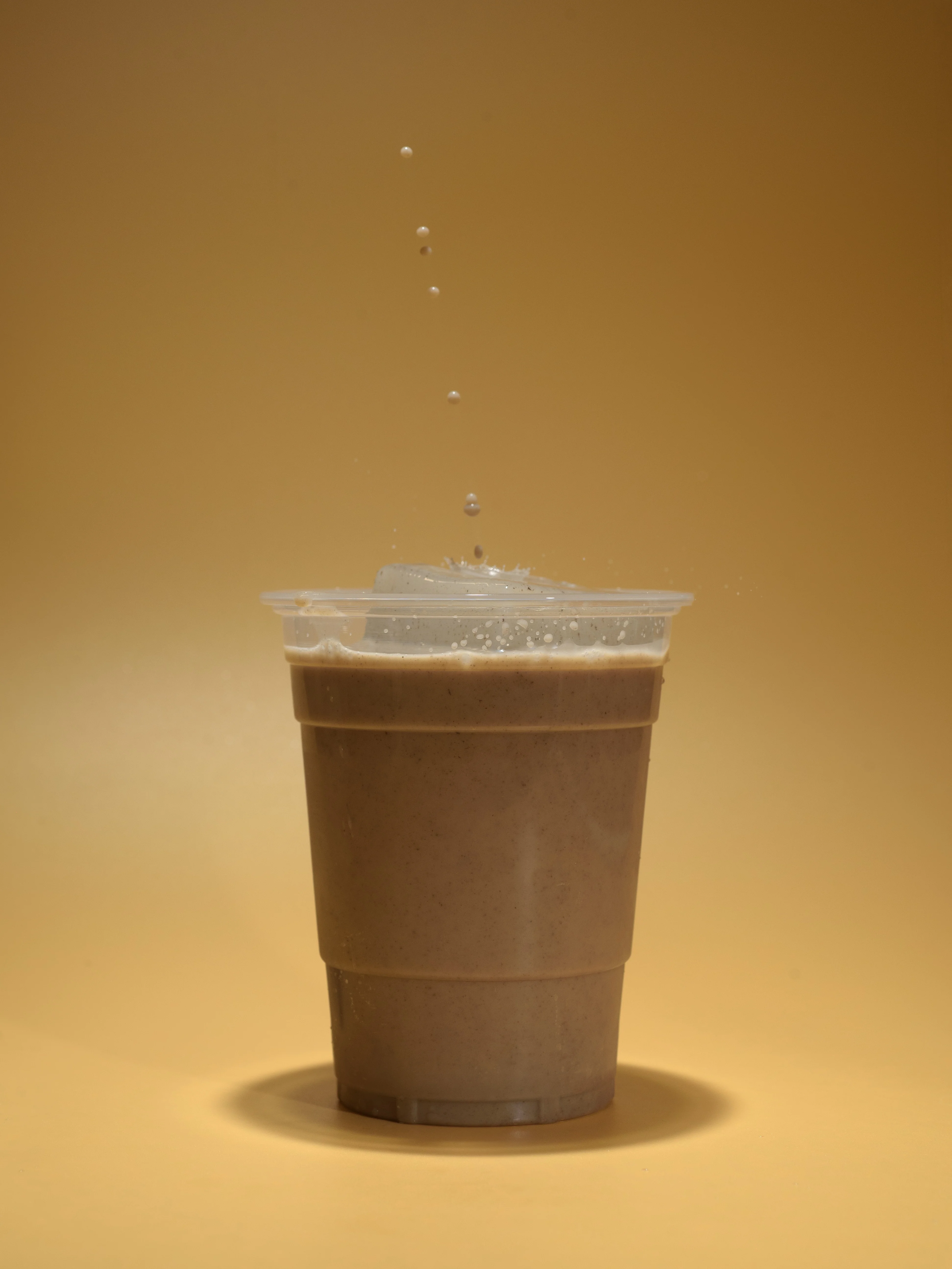 Chocolate milkshake in a clear cup with splashes