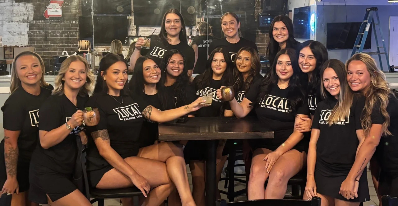 Group of restaurant staff posing together in branded shirts