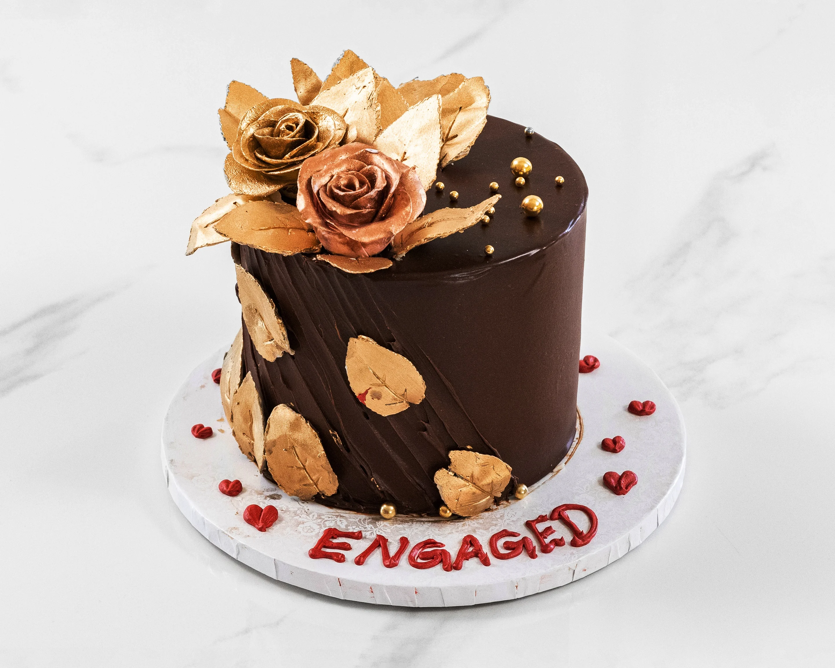 Elegant engagement cake with gold roses and decorative leaves
