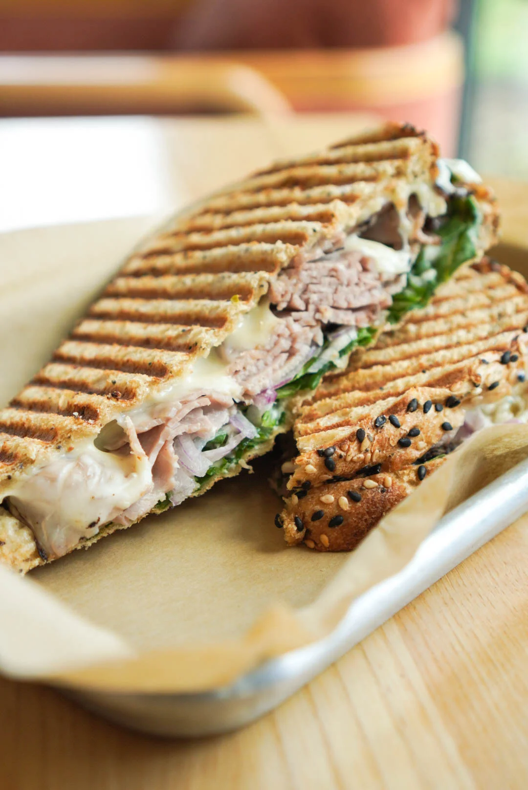 A grilled panini with deli meat, cheese, and fresh vegetables