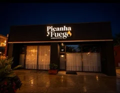 Restaurant exterior with illuminated Picanha Fuego signage at night