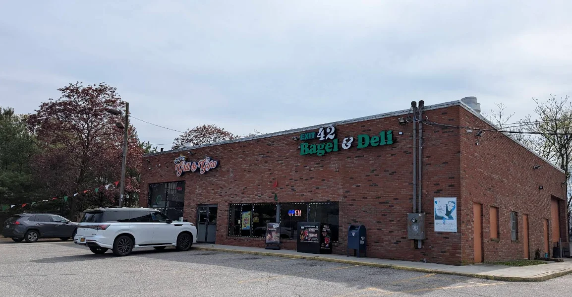 Exterior view of a bagel and deli shop with a welcoming sign