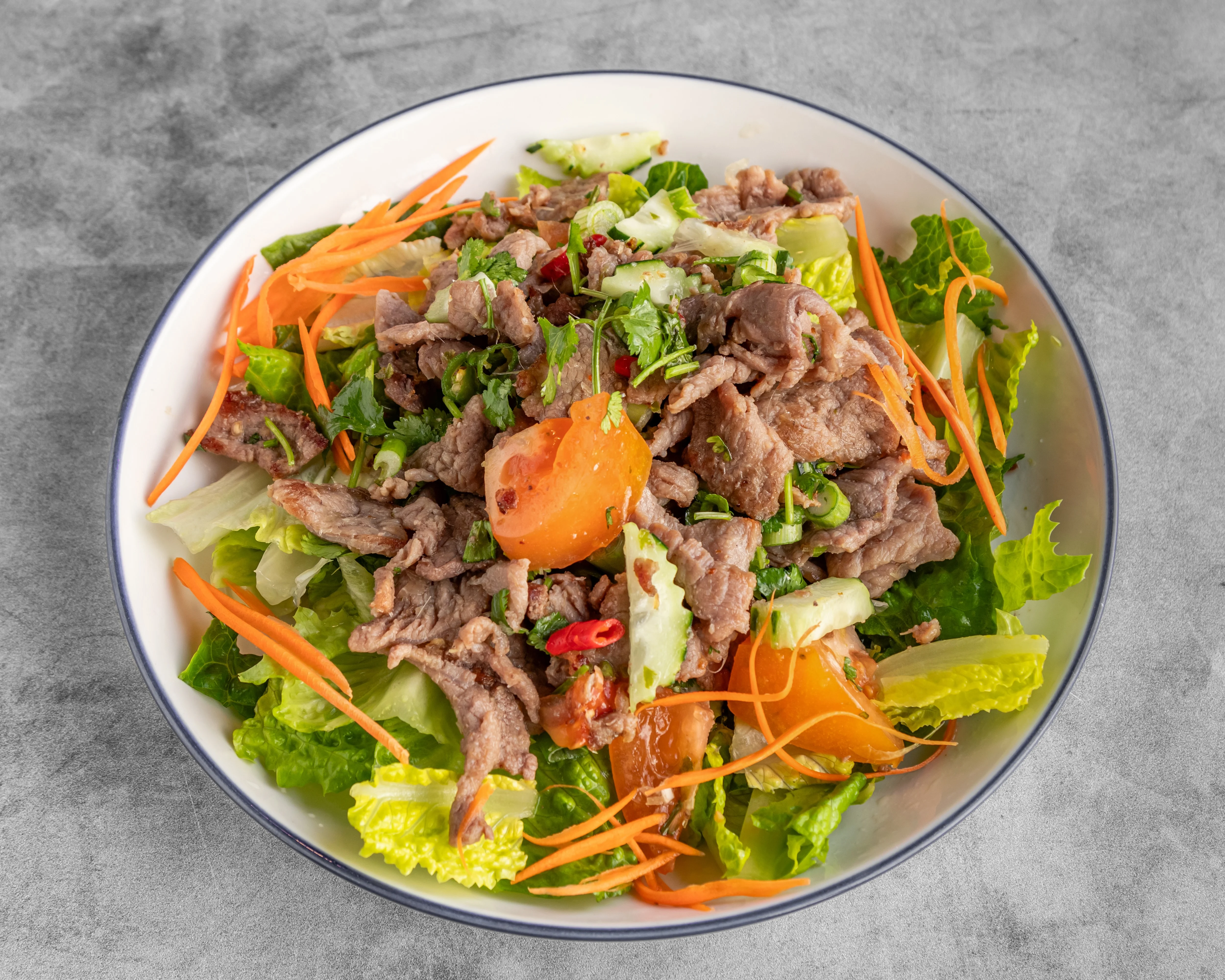 A vibrant beef salad with fresh vegetables and herbs.