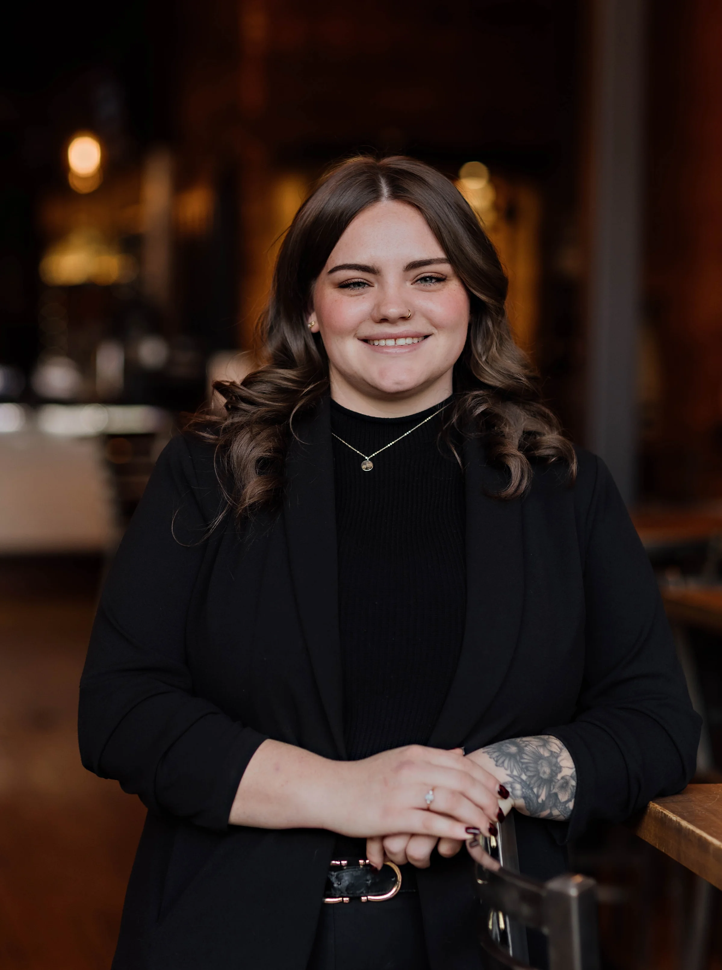 Smiling woman in a black blazer at a restaurant interior
