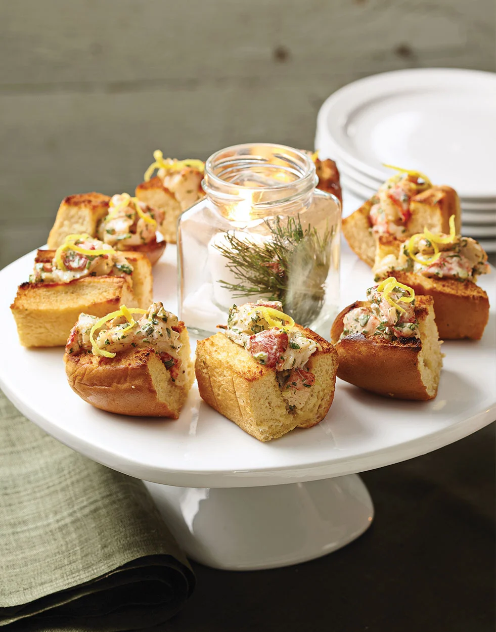 Savory lobster toast appetizers on a white cake stand