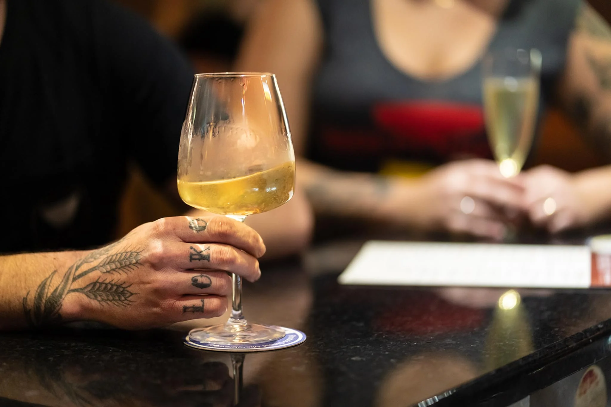 Close-up of a hand holding a glass of white wine at a bar