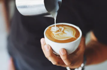 A barista pouring a cup of coffee