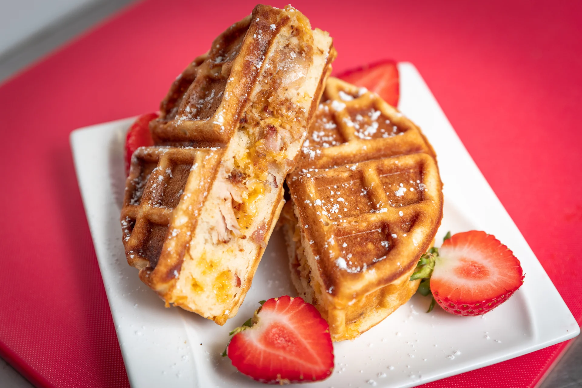 Savory chicken and waffle sandwich with strawberries