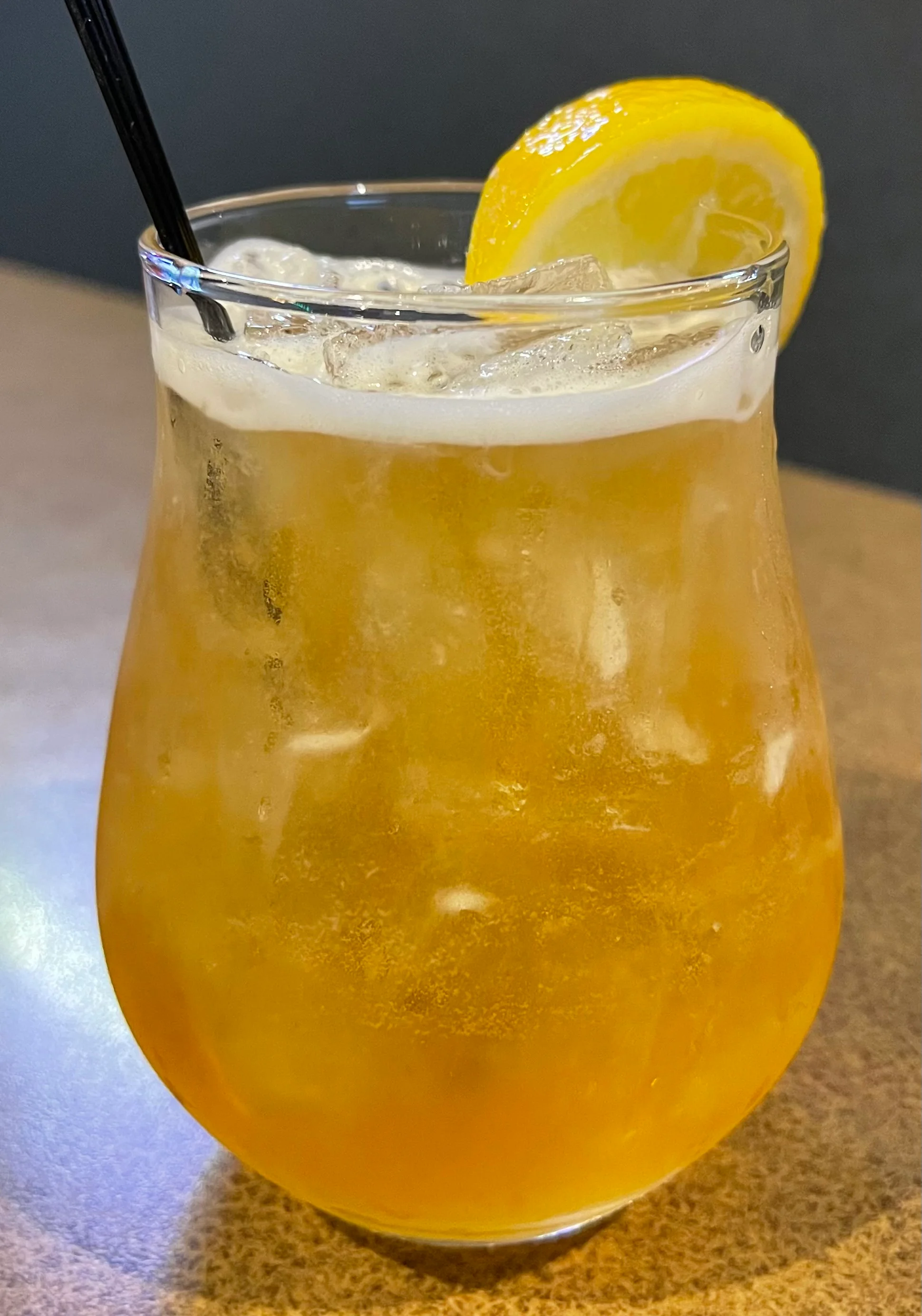 A refreshing glass of bourbon peach tea garnished with a peach slice.