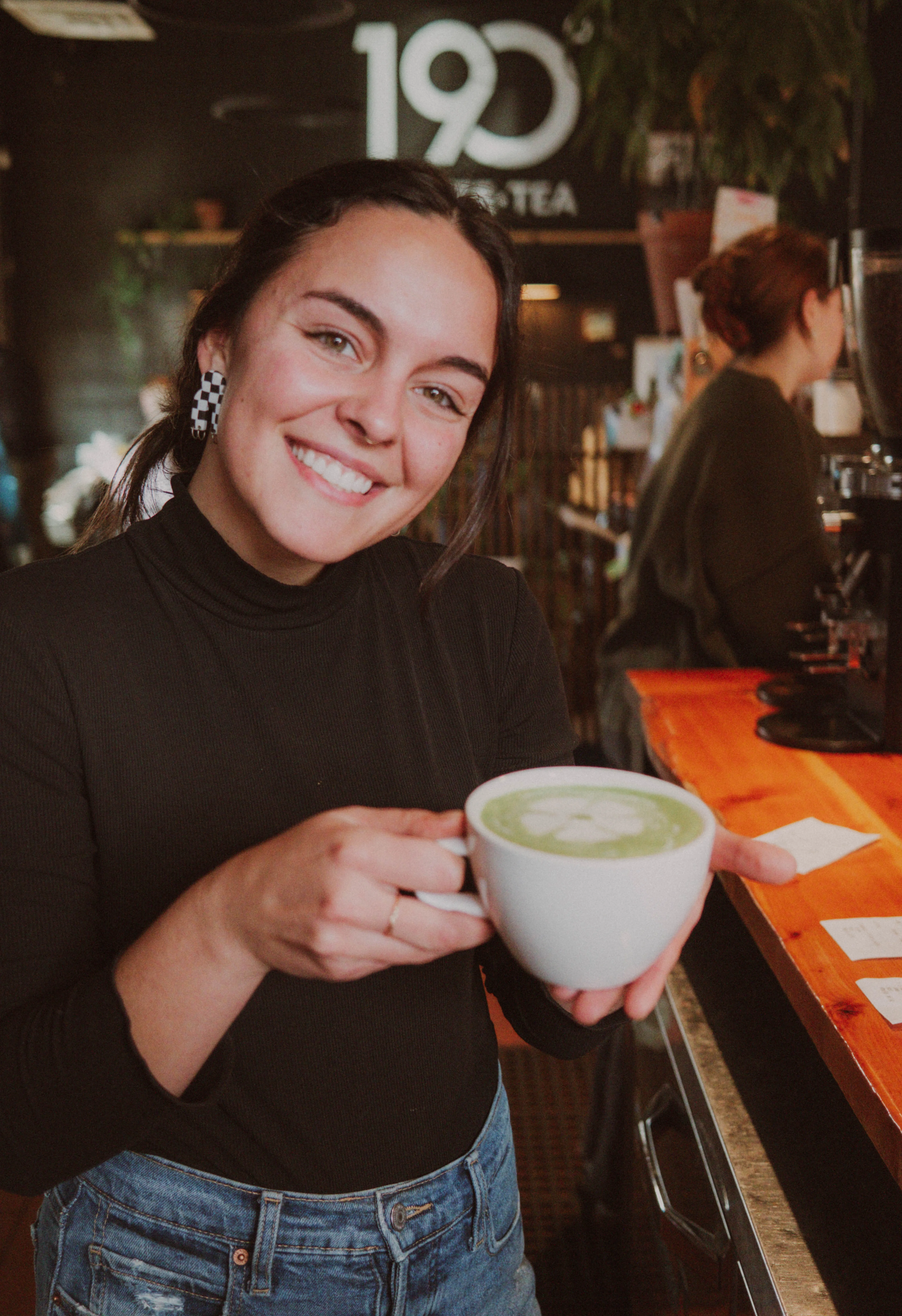 Barista serving matcha latte in a cozy café