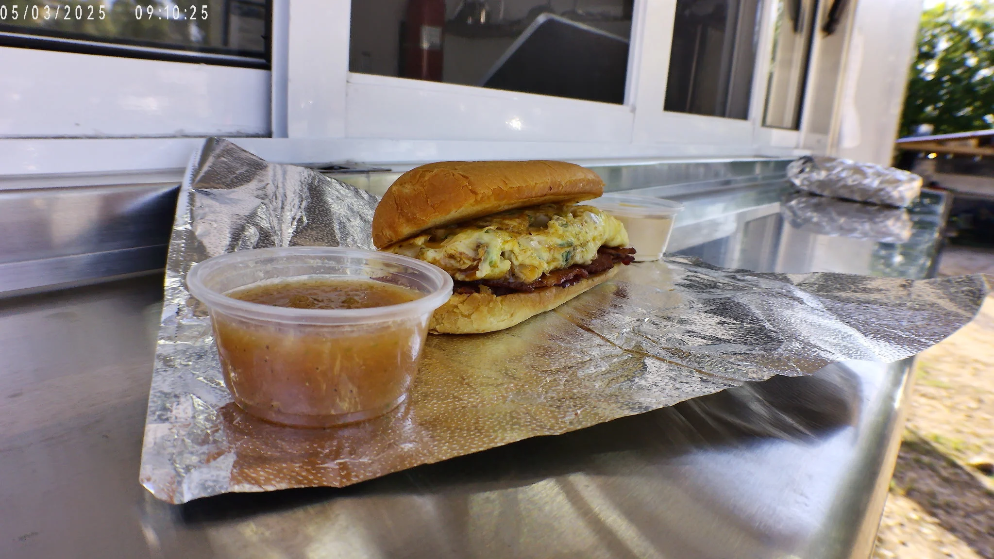 Breakfast sandwich with eggs and meat served with dipping sauces
