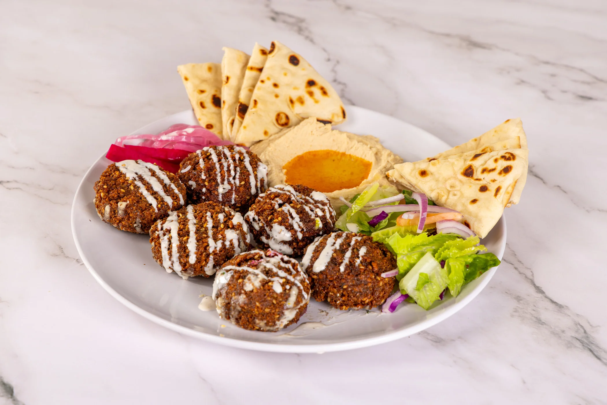 A delicious falafel plate with fresh vegetables and sauces.