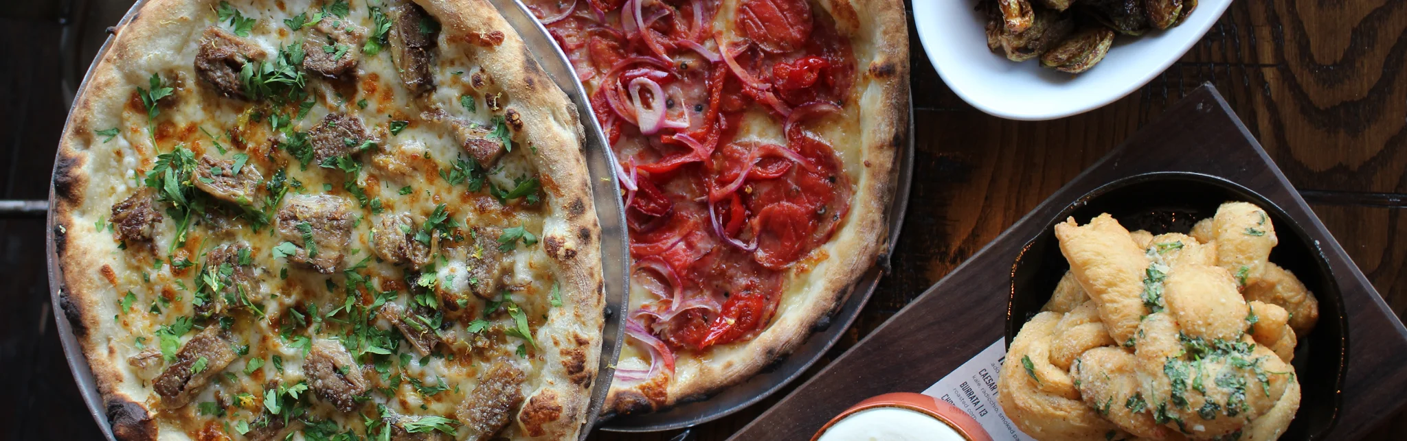 Gourmet pizzas featuring pepperoni and lamb in a rustic setting