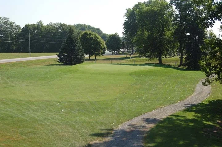 Lush green golf course with trees and gravel path