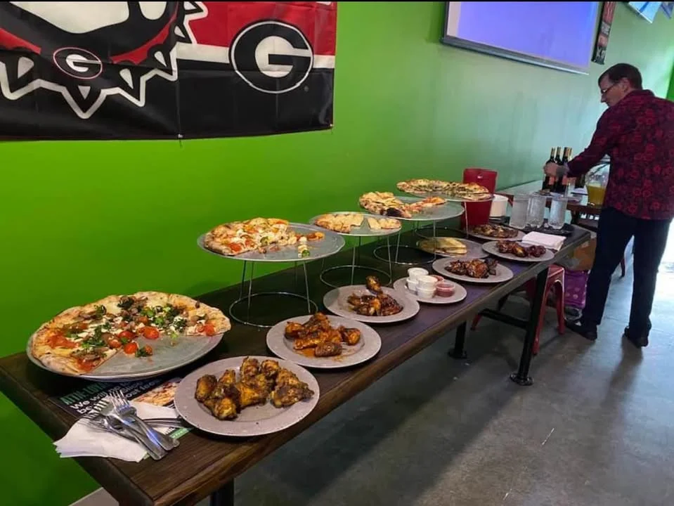 Variety of pizzas and wings at a casual dining setup