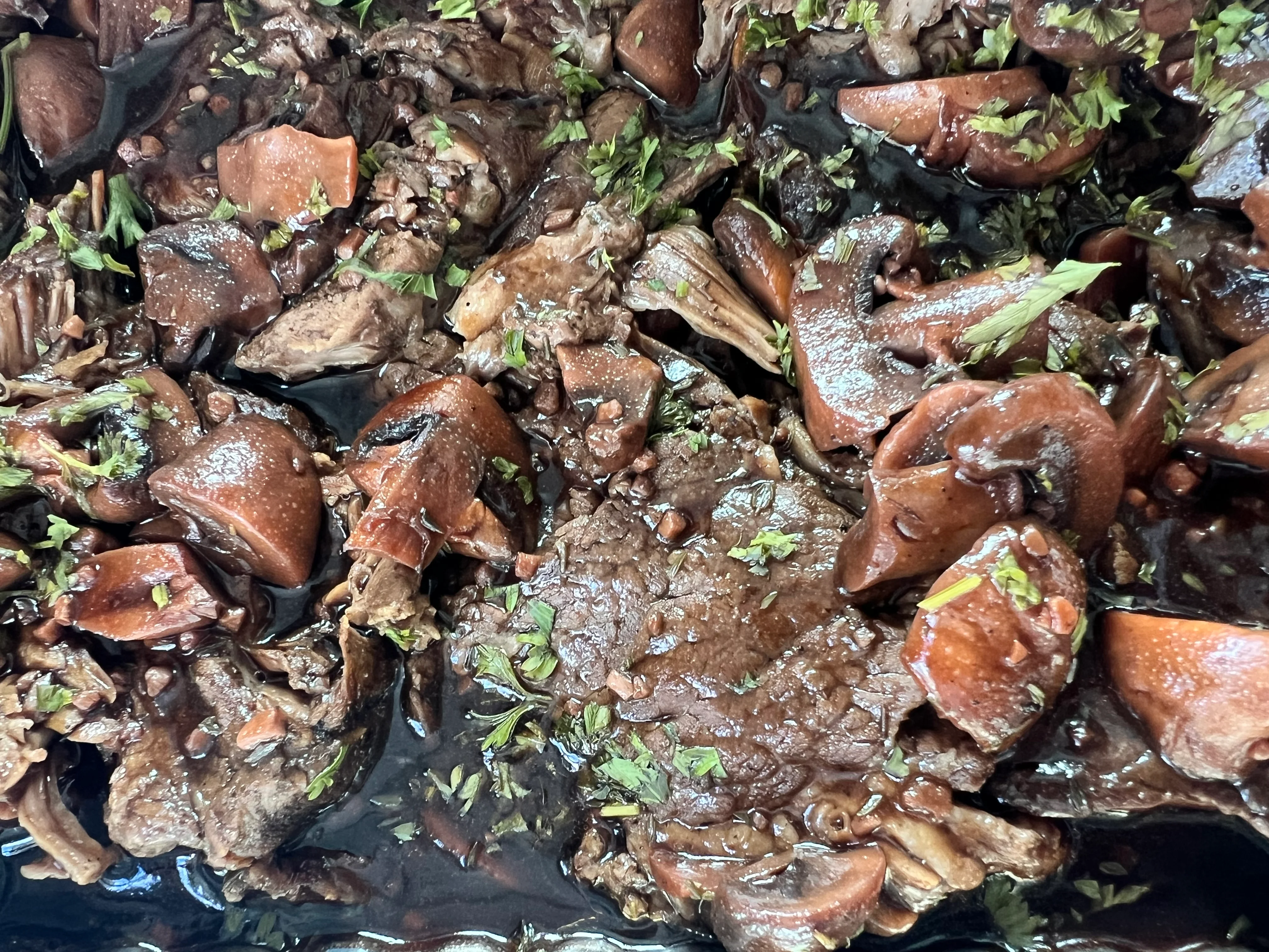 Close-up of braised meat garnished with fresh herbs