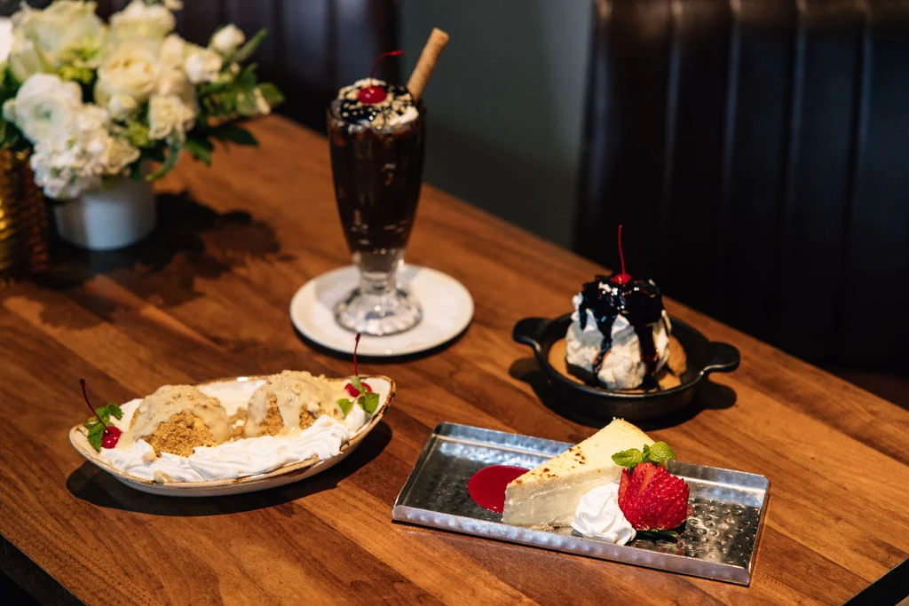 Delicious desserts including cheesecake, ice cream, and a milkshake on a wooden table.