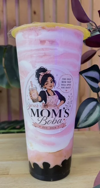 A beautifully layered pink drink with a swirl pattern, featuring a blend of flavors and black tapioca pearls at the base, served in a clear cup with a decorative label.