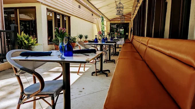 Covered patio with blue-glass table settings and cushioned bench seating at Seagrass Grille—romantic outdoor dining in Hilton Head