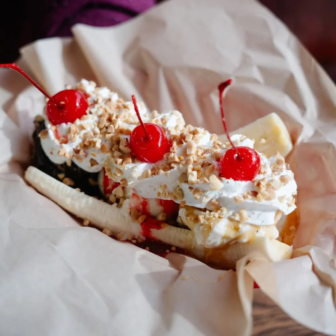 Classic American banana split dessert with whipped cream and cherries
