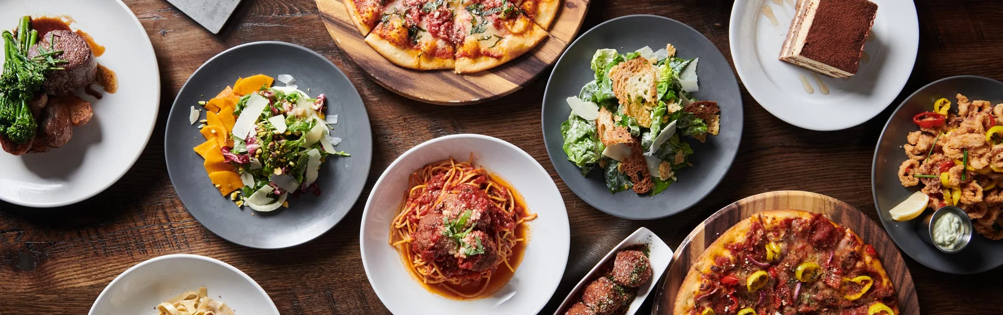 Italian feast featuring spaghetti and meatballs, pizza, and salads