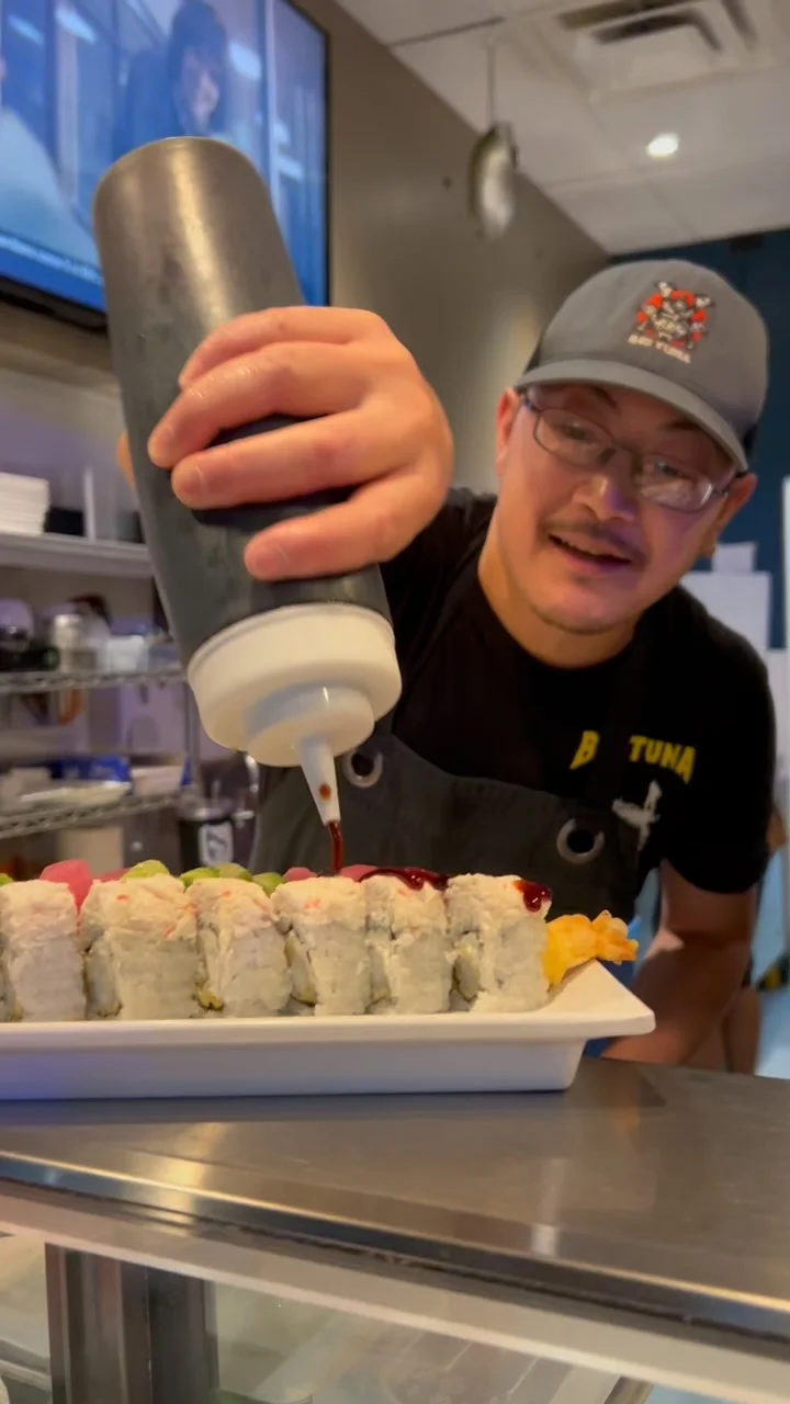 Chef drizzling sauce on sushi rolls in a Japanese restaurant