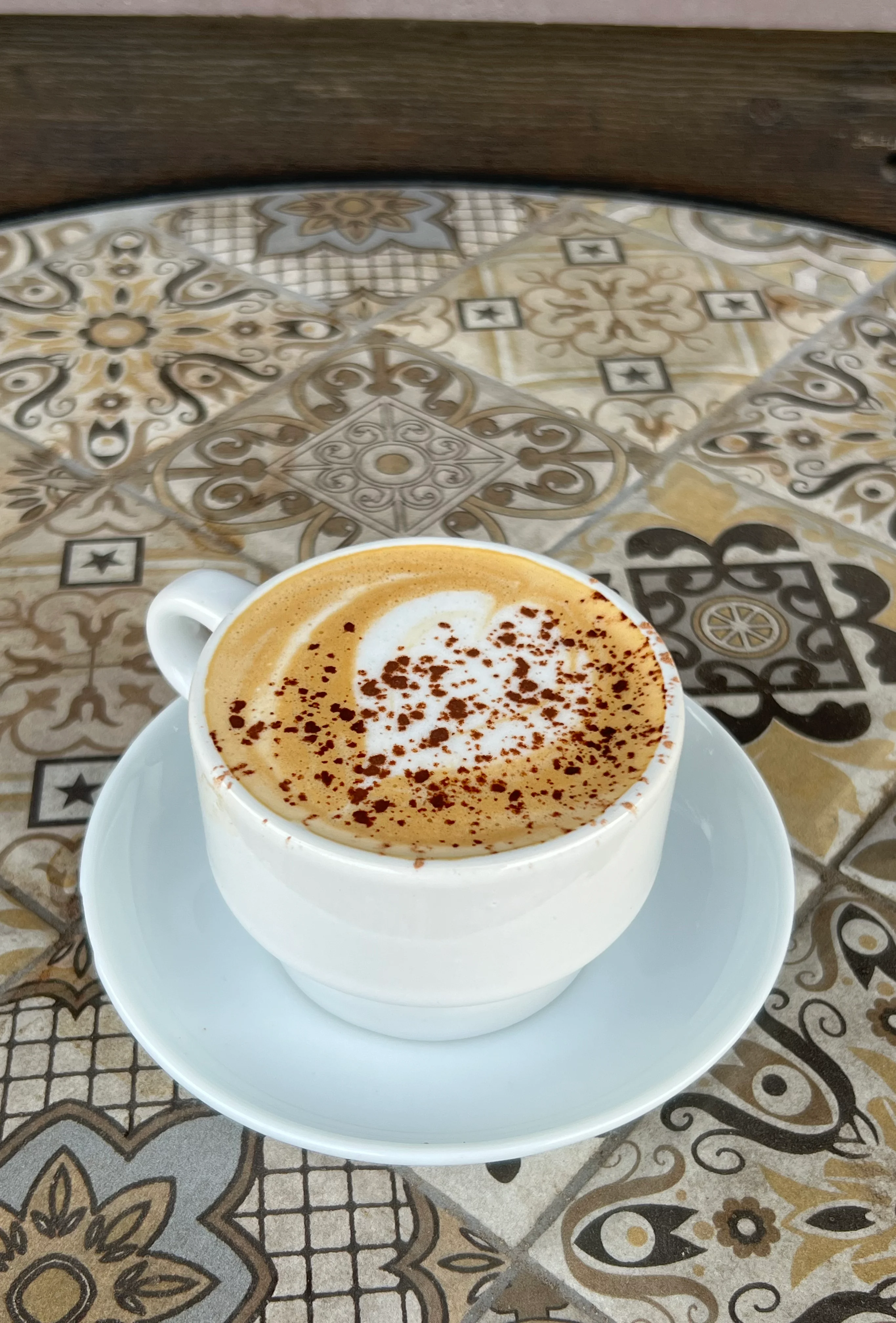 Cappuccino topped with cocoa powder on a decorative table
